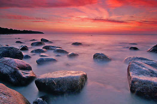 Coastal sunset with foreground rocks and red sky