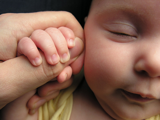 Baby holding parent's thumb