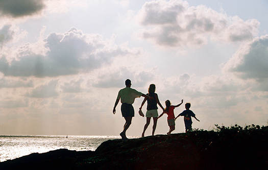 Family of four in silhouette walking on a beach