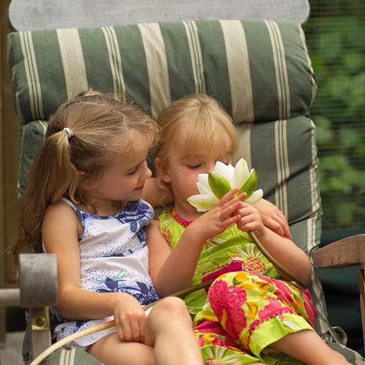 Two girls in a chair looking at a flower