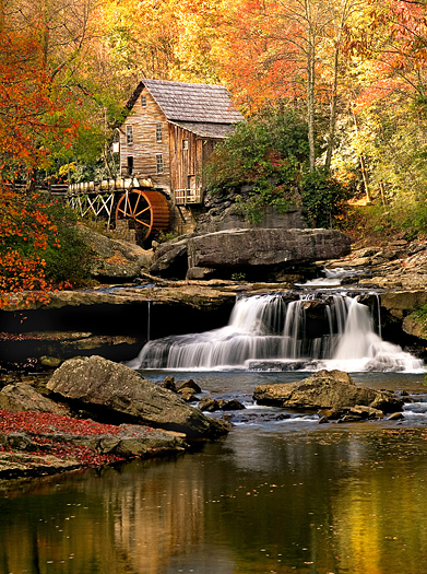 Fall scene at a mill with a water wheel and a small waterfall in the foreground