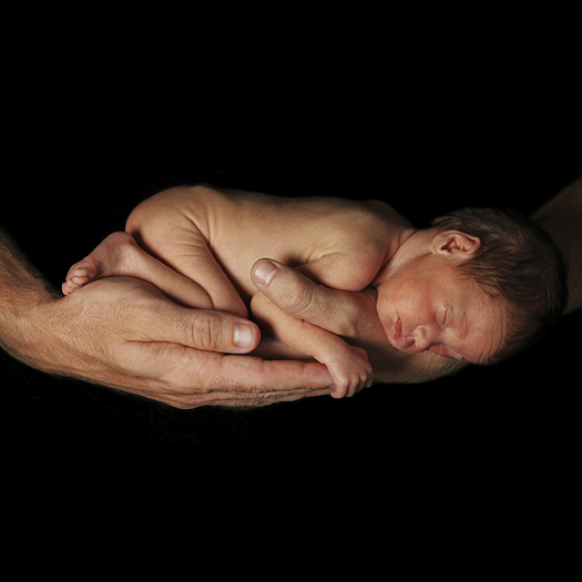 an infant asleep in a man's hands