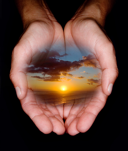 female hands holding image of beautiful sunset over the ocean