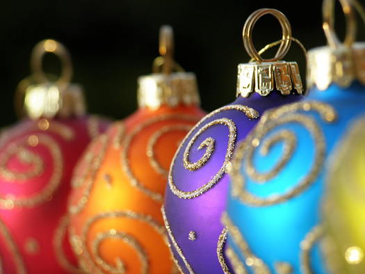 Close-up of multi colored Christmas baubles in a row with swirl decoration in gold