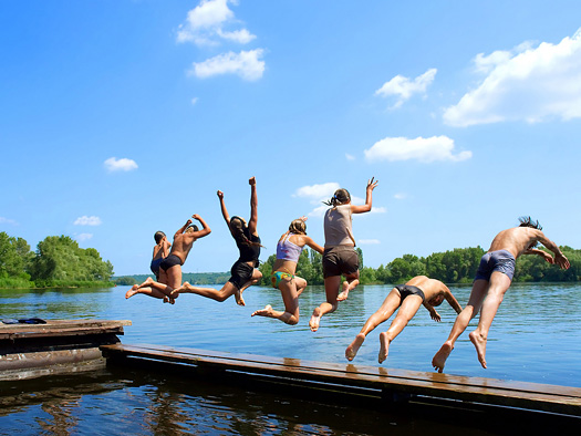 group of kids jumps into water from pier. Shot in June, Dnieper river, Ukraine.