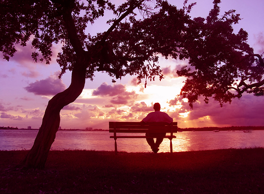 Man sitting on a bench enjoying sunset on the lake
